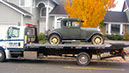 A Ron May Towing flatbed truck transporting a cliassic 1930's car
