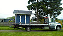 A Ron May Towing truck carrying a shed